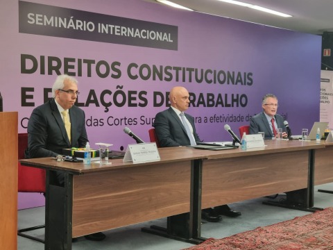 Foto de três autoridades sentadas à mesa do seminário internacional da Enamat