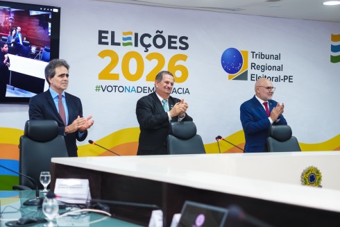 Foto mostra três homens de terno em pé enquanto batem palmas