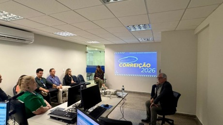 Fotografia onde aparecem adultos sentados, reunidos numa sala de audiência