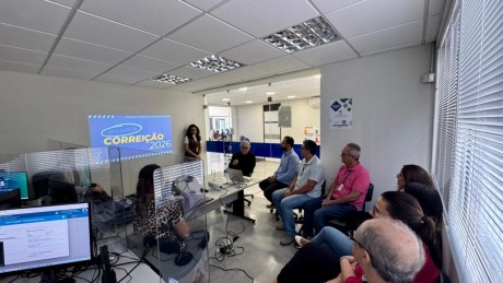 Na fotografia, aparece um grupo de adultos, sentados, reunidos numa sala de audiências