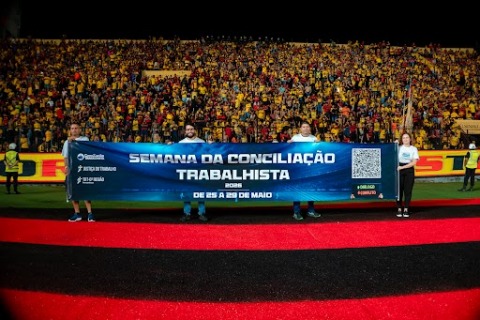 Quatro servidores estendem uma faixa no gramado do estádio do Sport lotado