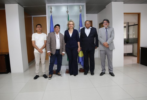 foto de cinco autoridades. Em pé, dentro de uma sala de reuniões e junto das bandeira de Recife, Pernambuco e do Brasil