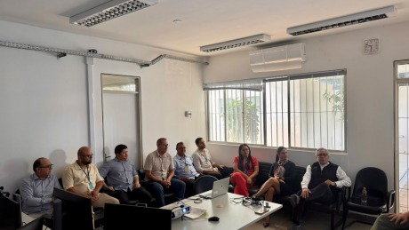 Na foto, aparecem nove adultos sentados na sala de audiências de uma Vara