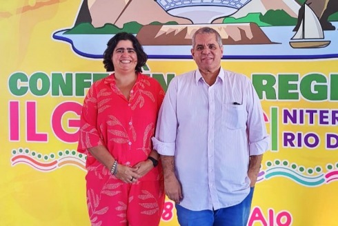 Foto da juíza do TRT-6 Renata Nóbrega e do ministro do TST Antônio Gonçalves em frente ao cartaz da 10ª Conferência Regional da ILGA LAC