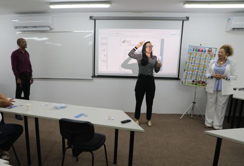 foto aluna em pé na frente da sala fazendo sinais