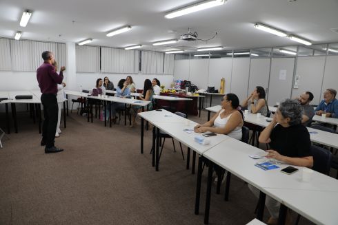 foto de sala de aula; alunos sentados; professores em pé fazendo sinais