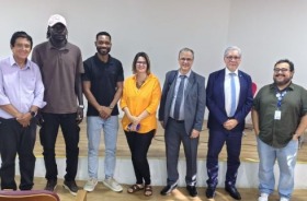 foto sete pessoas, sendo seis homens e uma mulher em pé em frente ao palco do auditório