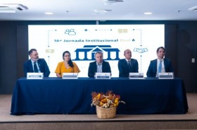 foto de mesa de honra na abertura do evento com cinco autoridades; ao fundo, telão de projeção com logo do evento
