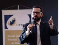 Fotografia de um homem, vestindo paletó, palestrando no auditório da Escola Judicial do TRT6