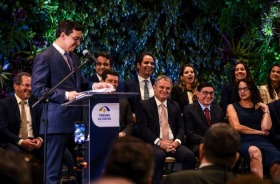 foto homem falando ao púlpito; ao fundo, autoridades sentadas em cadeiras