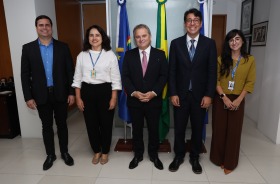 Foto mostra cinco adultos em pé, lado a lado