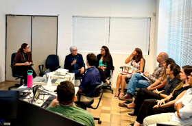 fotografia onde aparecem 11 adultos sentados em reunião numa sala de audiências