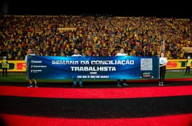 Quatro servidores estendem uma faixa no gramado do estádio do Sport lotado
