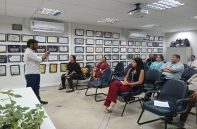 foto homem em pé ministrando oficina; pessoas sentadas na plateia