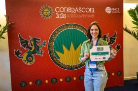 Fotografia onde aparece uma mulher segurando um certificado de premiação