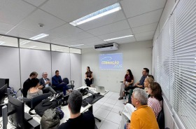 Na foto, aparece um grupo formado por 13 adultos sentados numa sala de audiências