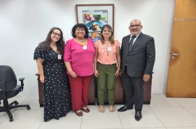 Foto. Representantes do Ministério do Trabalho e desembargador Fábio Farias. De pé. Em frente a uma parede branca. 