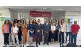 Fotografia onde aparece um grupo de adultos, perfilados, no hall de entrada de uma Vara do Trabalho