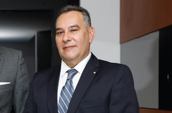 Foto mostra um homem usando terno azul marinho e camisa branca. Tem cabelo grisalho