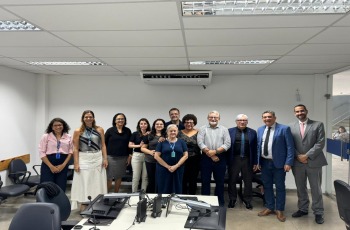 Fotografia onde aparece um grupo de 12 adultos perfilados numa sala de audiências