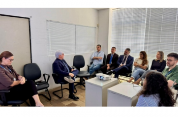 Fotografia onde aparecem 8 adultos sentados numa sala de audiências