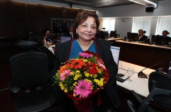 Fotografia de uma senhora segurando um buquê de flores