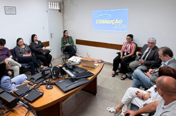 Fotografia onde aparece um grupo de adultos, sentados em círculo, numa sala de audiência