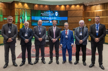 Na foto, sete homens perfilados num auditório