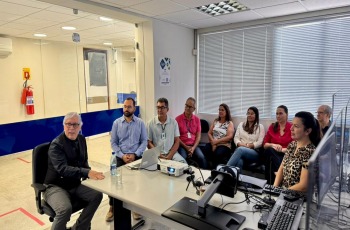 Na fotografia, aparece um grupo de adultos, sentados, reunidos numa sala de audiências