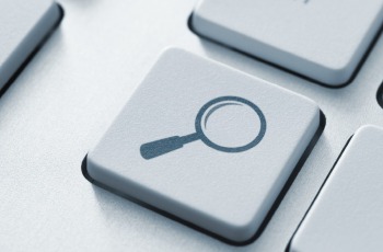 Tecla branca com símbolo de lupa, em teclado de computador